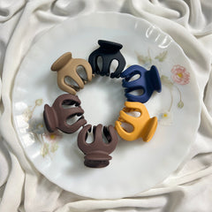 Set of colorful hair clips on a decorative plate with a white fabric background